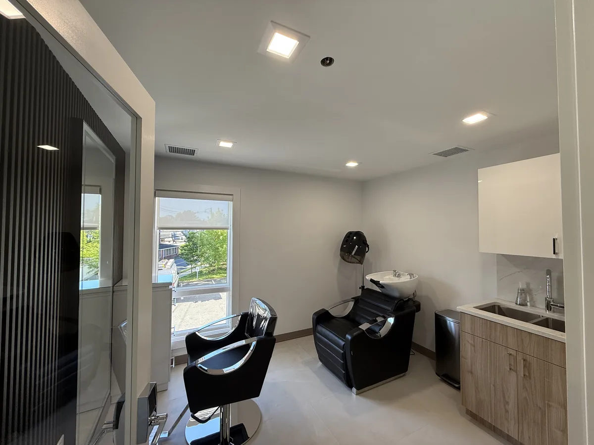 Salon suite with recessed ceiling lights over styling chairs and a shampoo station